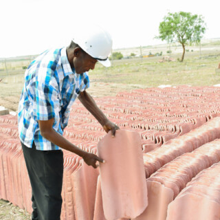 Mr. Peter Mwaura Quality Control Manager Inspecting finished roofing tiles in the yard
